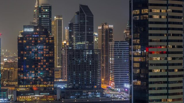 Aerial view to Dubai Business Bay and Downtown with the various skyscrapers and towers along waterfront on canal night timelapse. Buildings uner construction