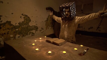 Ghost with cage on his head reading spells next to crucified body in basement.