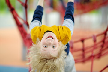 ?ute perky preschooler boy having fun on outdoor playground. Spring/summer/autumn active sport...