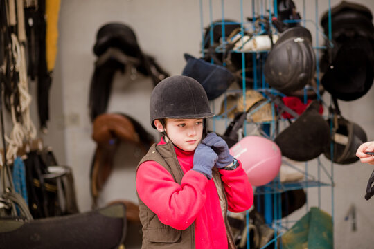 Hispanic boy wear protective Horse riding helmet for safety in equitation sport. Riding school