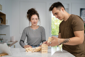 young couple woman and man play jenga game at home on the table