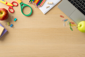 Embrace the convenience of online learning with this top-down photo featuring laptop, fruits, notepad, colorful pencils and stationary on wooden background. Ample copy-space available for text or ads
