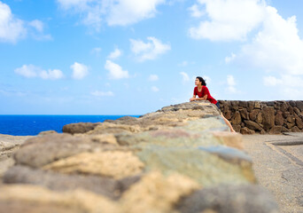 Young woman leaning against stone wall overlooking Hawaiian ocean - Powered by Adobe