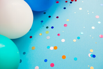 Beautiful blue background with glitter confetti and colorful air balloons, celebration card with copy space