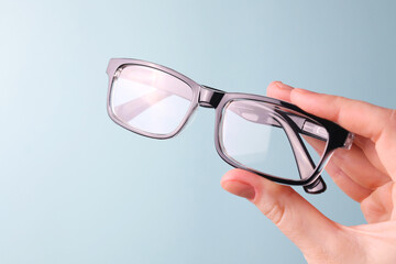 glasses for vision correction in the hand on a colored background with space for text