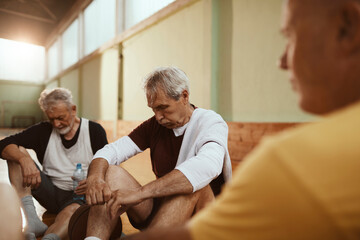 Fototapeta premium Senior men taking a break from playing basketball in an indoor gym