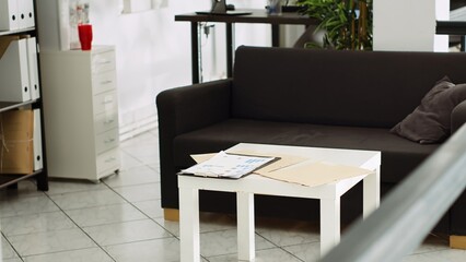 Small business open floor plan with couch and table, casual spacious empty startup coworking space in marketing department agency. Modern furniture and desks supplies, company workstations.