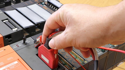 The electrical engineer connects the communication cable to the PLC automaton. Cable connection...