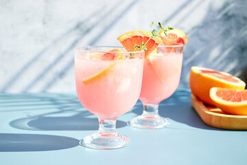 Chilled cocktails with fresh grapefruit juice, served with a sprig of thyme and fresh fruit slices. Refreshing summer cocktails with citrus fruits.