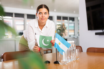 Businesswoman arranging the flags of Argentina and Pakistan for a presentation and negotiations