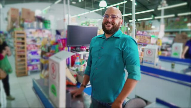 Happy supermarket employee standing at cashier checkout smiling at camera, South American Brazilian Grocery Store Portrait Manager