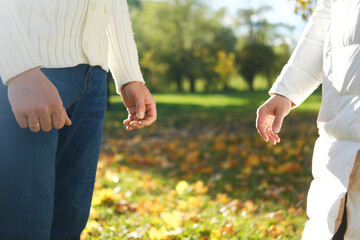 A man and a woman stand opposite each other in an autumn park. Hands shot close up