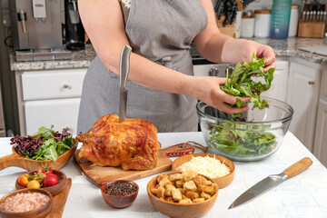 Cooking Caesar salad. A chef adds lettuce leaves to a glass bowl in a home kitchen.