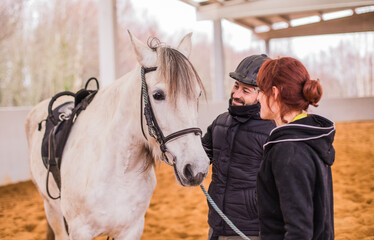 Hippotherapy assistance therapist with medical disability patient on equestrian riding hall.