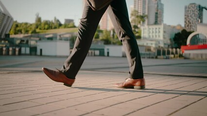 Male legs in classic trousers move along tiled pavement