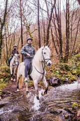 Horse riding, Way of st James in Fragas do Eume, Galicia. Hispanic pilgrim mid couple equitation