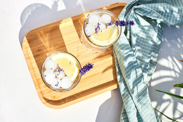 Chilled cocktail with lavender and citrus. Summer drink, soda with lemon and sprig of lavender on a bright sunny day. Detox water with citrus