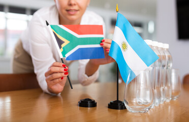 Preparing for business presentation - secretary places flags of Argentina and South Africa on the negotiating table