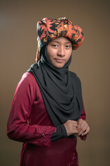 A young malay teenager girl wearing a traditional Negeri Sembilan costume on brown color background