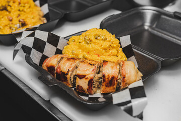 Risotto served on a delivery plate with a chicken breast of bacon