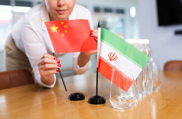 Little flag of Iran on table with bottles of water and flag of China put next to it by positive...