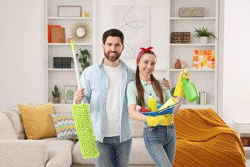 Spring cleaning. Couple with detergents and mop in living room - obrazy, fototapety, plakaty