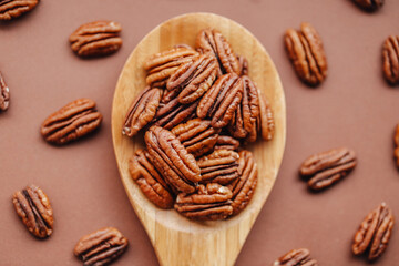 shelled pecans. Pecan nuts in a wooden spoon on a brown background. Keto diet ingredient. Nuts and seeds. Useful healthy snack.