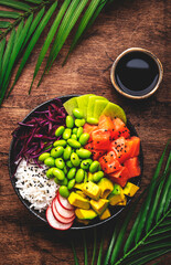 Hawaiian poke bowl with salmon, avocado, radish, edamame beans, red cabbage and white rice. Soy...