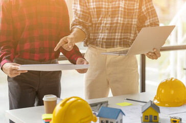 Engineer and contractor planning projects together at desk with blueprints.