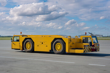 Yellow pushback tug on the airport apron. Low-profile tractor for moving aircraft along the airport...
