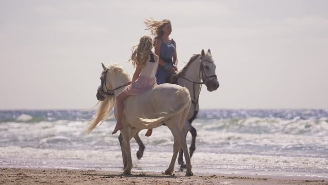 Two Girls Riding Horses By The Beach
