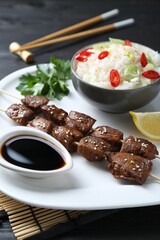 Tasty chicken meat glazed in soy sauce served with rice on black table, closeup
