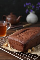 Delicious chocolate sponge cake and nuts on wooden table, closeup