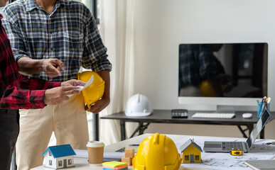 Engineer and contractor planning projects together at desk with blueprints.
