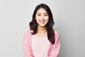 Fototapeta premium Portrait of a beautiful young asian woman smiling on gray background