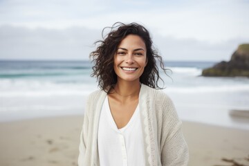 Portrait of smiling young woman standing on beach at the seaside