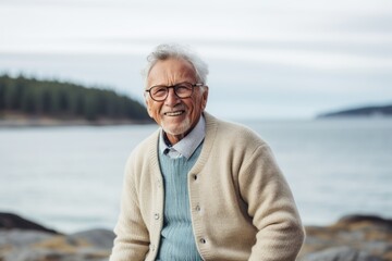 Portrait of happy senior man in eyeglasses looking at camera and smiling while standing on the beach