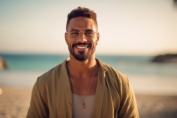 Portrait of a handsome young man with sunglasses smiling on the beach