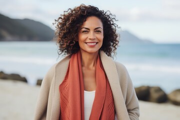 Portrait of smiling woman with curly hair standing on beach at the day time