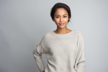 Obraz premium Portrait of young beautiful asian woman in white sweater against grey background