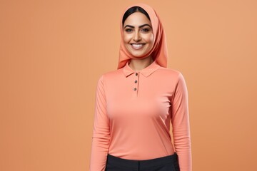 Obraz premium happy muslim woman in hijab looking at camera isolated on orange background