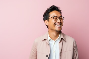Portrait of a happy young asian man with glasses against pink background
