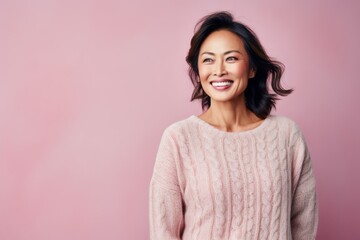 Fototapeta premium Portrait of a smiling asian woman looking at camera isolated over pink background