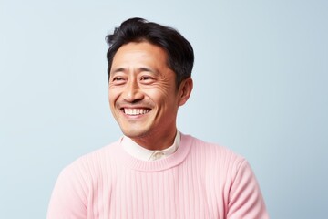 Portrait of a happy Asian man looking at camera over blue background