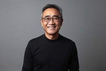 Obraz premium Portrait of a happy senior Asian man in black sweater on grey background