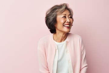 Obraz premium Portrait of a smiling senior asian woman standing against pink background