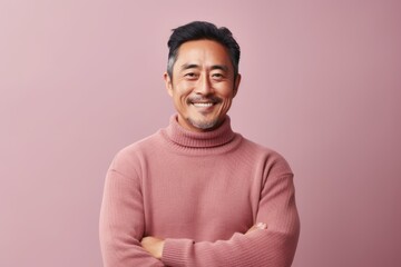 Portrait of a smiling asian man with folded arms isolated over pink background