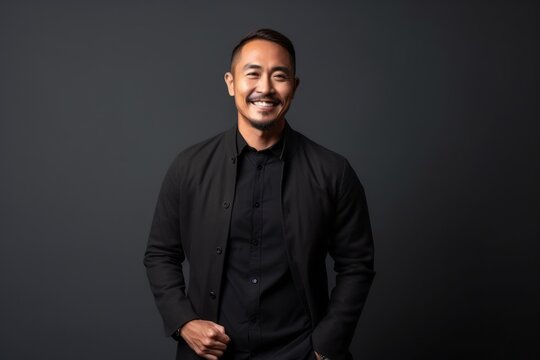 Portrait of a smiling asian man in black shirt on grey background