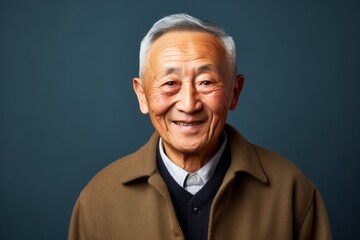 Fototapeta premium Portrait of a senior asian man smiling against blue background.