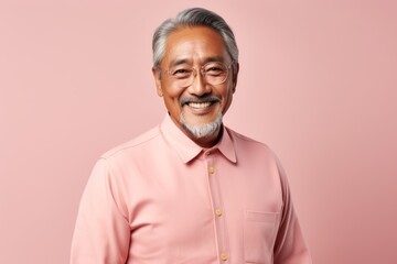 Fototapeta premium Portrait of a smiling senior asian man looking at camera isolated over pink background